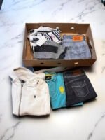 Ropa y cuero vintage en caja misteriosa con prendas variadas.