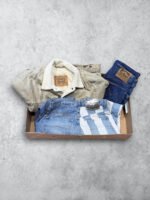 Ropa vintage de cuero y mezclilla en caja, estilo retro y clásico.