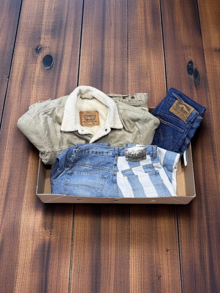 Ropa vintage de cuero y mezclilla en caja misteriosa, ideal para amantes de prendas únicas y de cali.