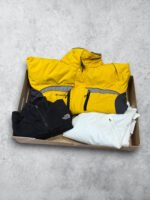 Chaqueta amarilla y ropa vintage de cuero y nylon en caja de cartón.